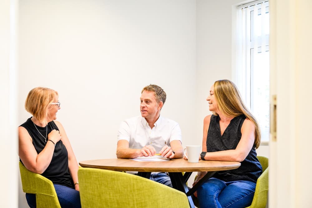 The Tudor Estates Team sat around a meeting table, talking.